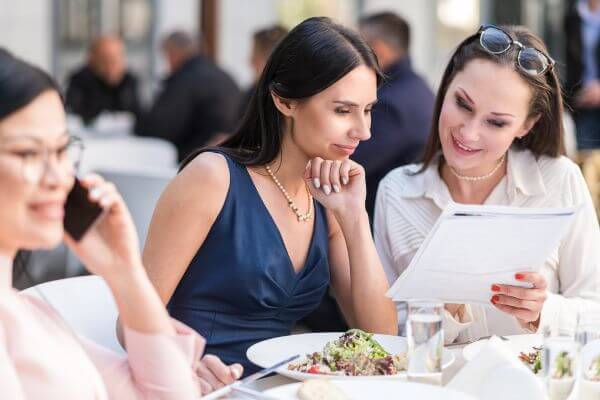 Image of the women getting their meal together while promoting something to each one and the other is answering her phone call.