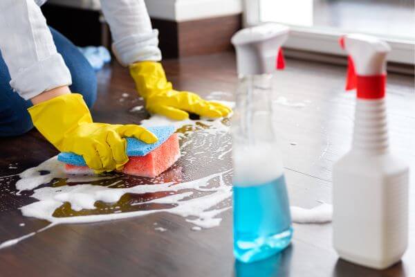 Picture of the woman hand wearing ag gloves while holding a phone cleaning the floor.