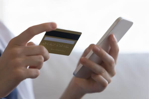 Picture of a woman holding a card and phone to deposit for savings.