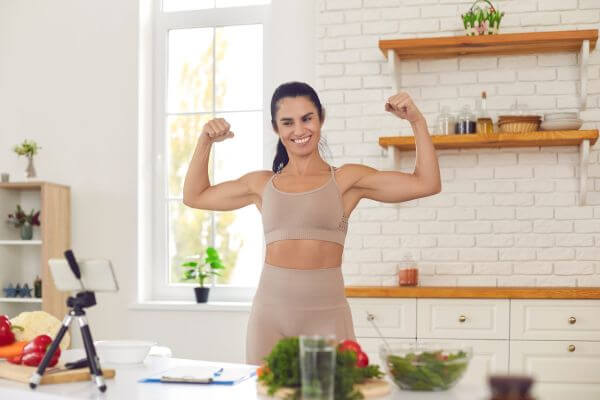 Image of a fitness coach filming her self and doing one of side hustle job for mom from home.