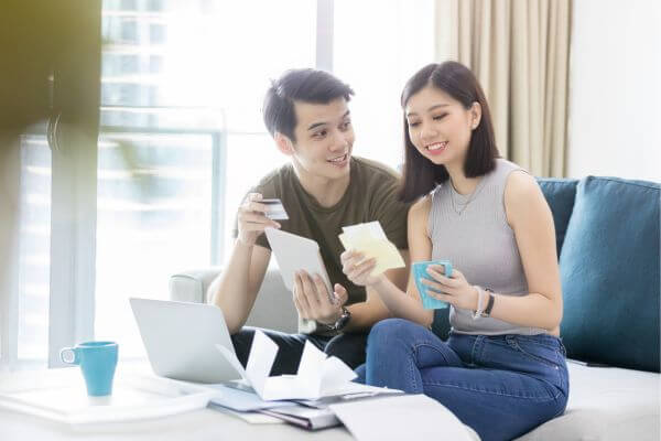 Image of a man and woman with their bills and laptop searching for ways on how to deal with debt and become a financial freedom.