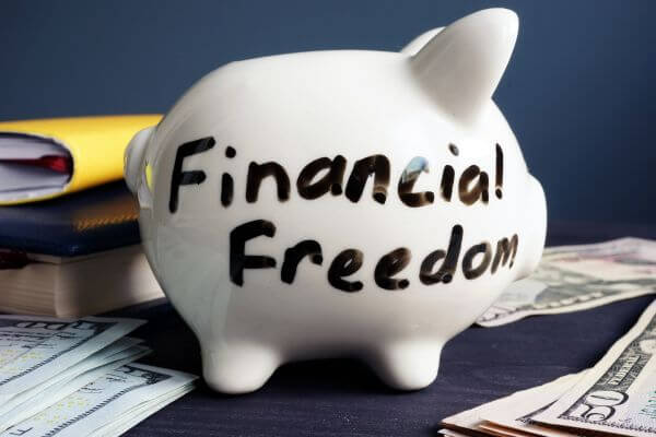 Image of a piggy bank, notebooks, and dollar bills referring to financial freedom.