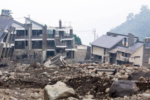 Picture of destroyed houses caused by a natural disaster and one of the examples of unexpected expenses.