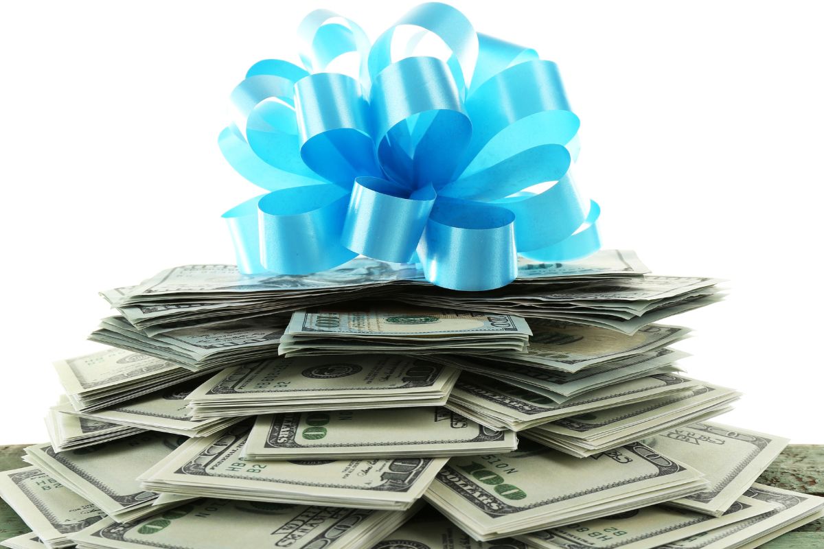 Picture of a stack of hundred dollar bills with a bow on top.