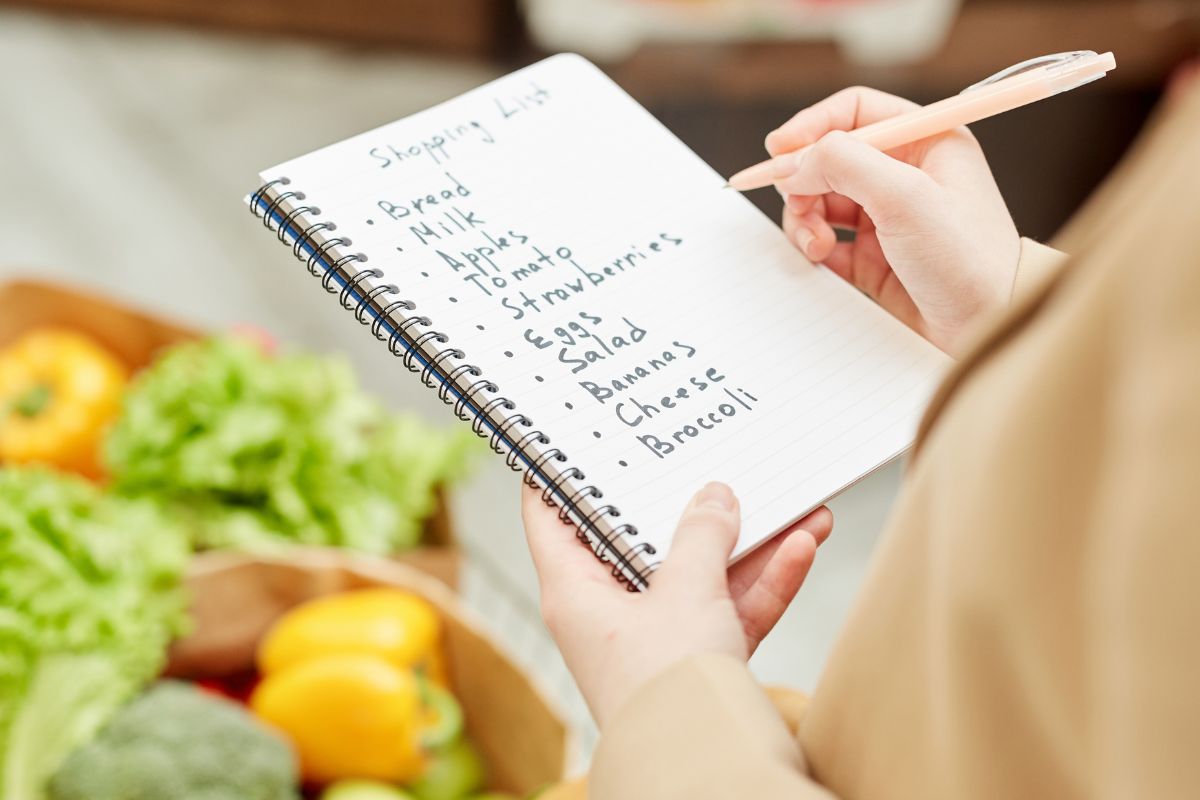 Image of a woman monitoring her groceries in the notebook to keep on sticking to her shopping list.