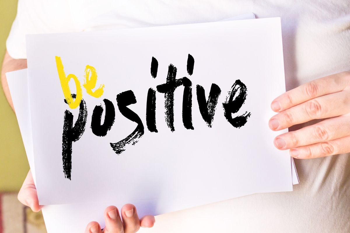 Photo of a woman holding a paper with positive wording.