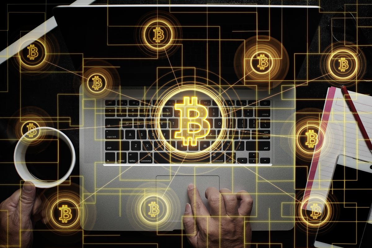 A foto mostra a mão de um homem investindo em Bitcoin.