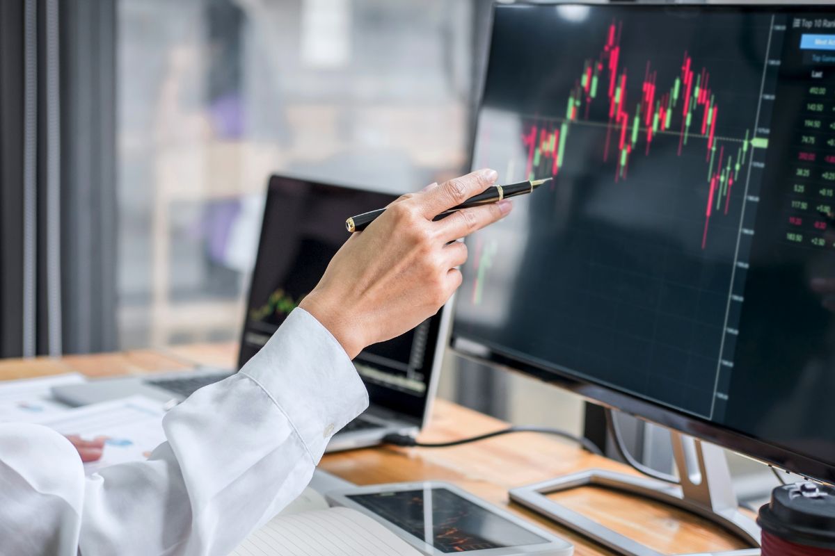 Image of a man's hand monitoring stocks.