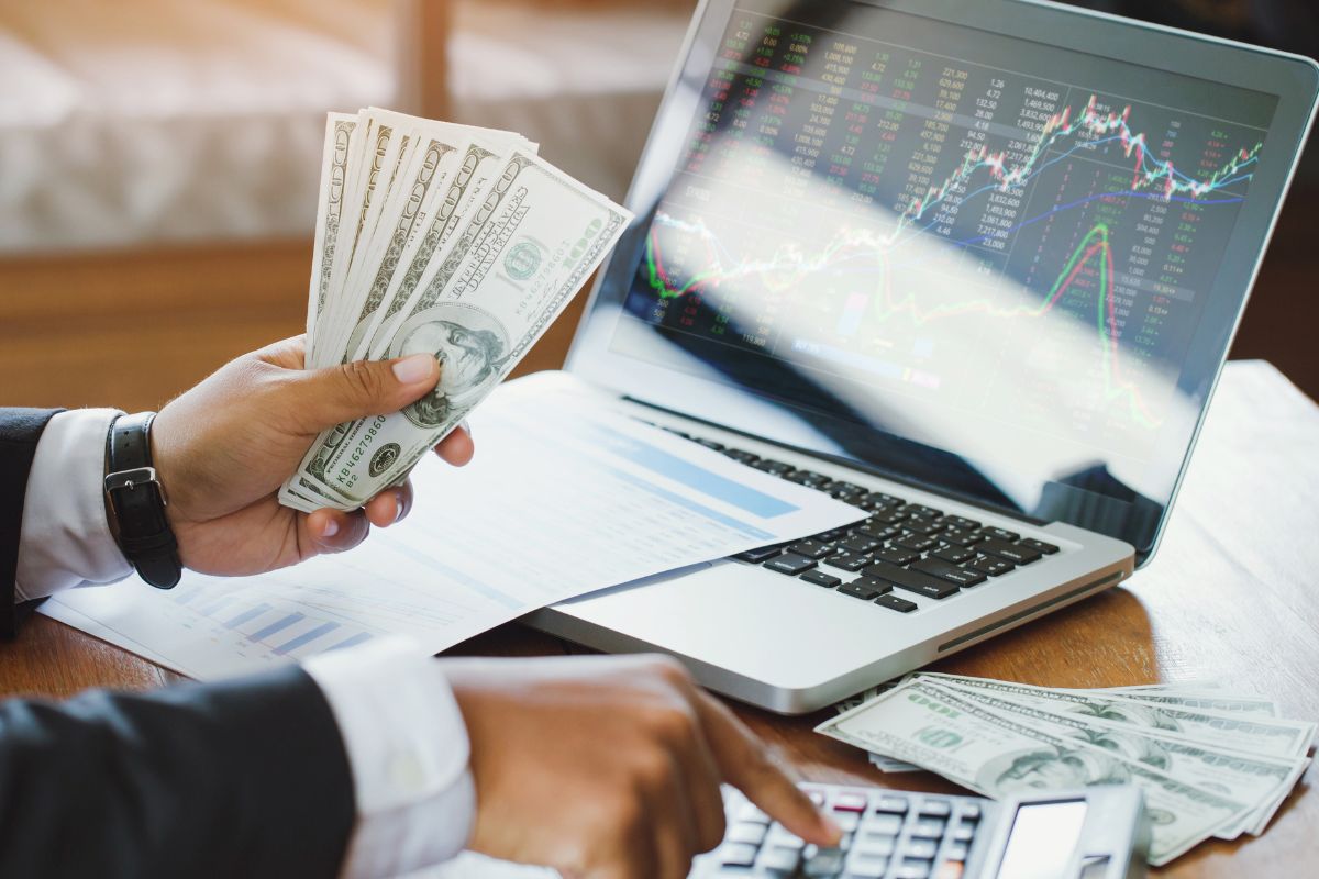 A man's hand making money in the stock market. 