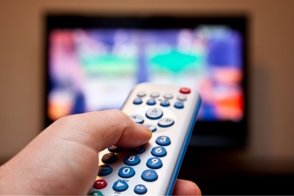 A man's hand watching a television.