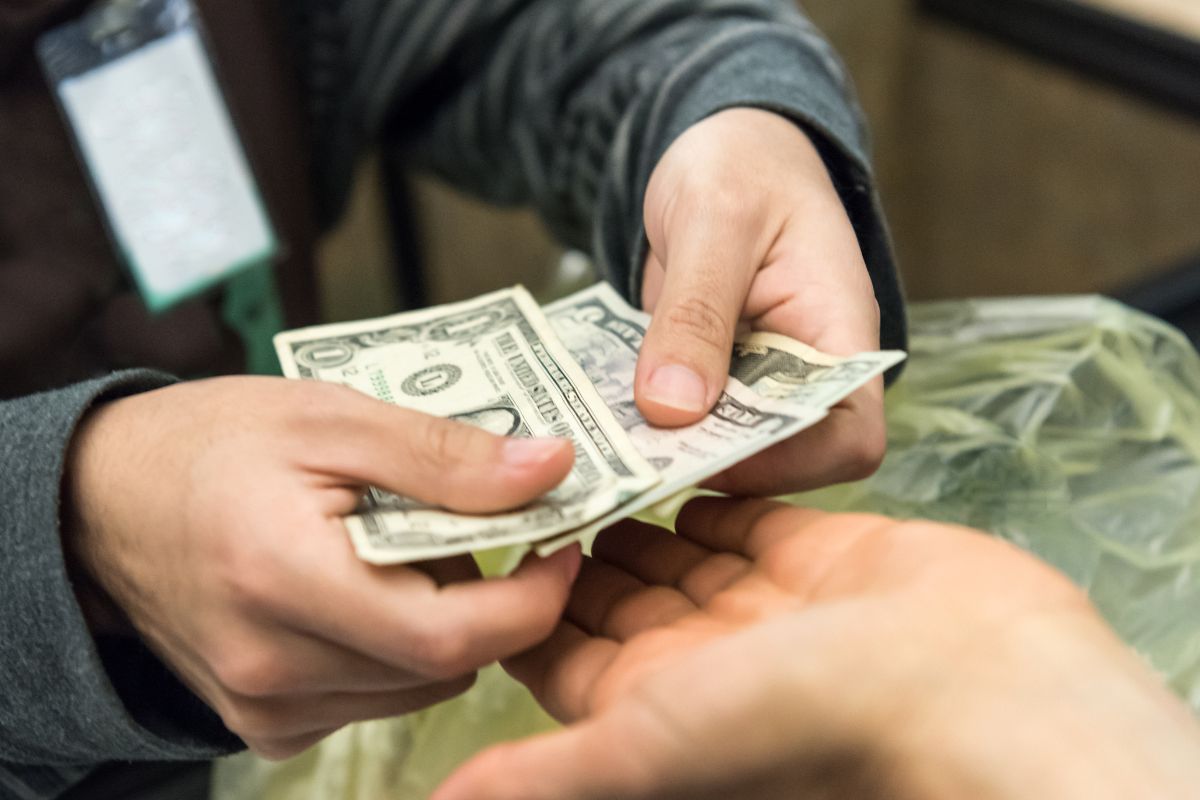 The image shows a man paying with cash.