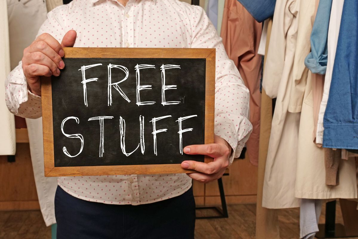 A man's hand holding a board with free stuff wording.