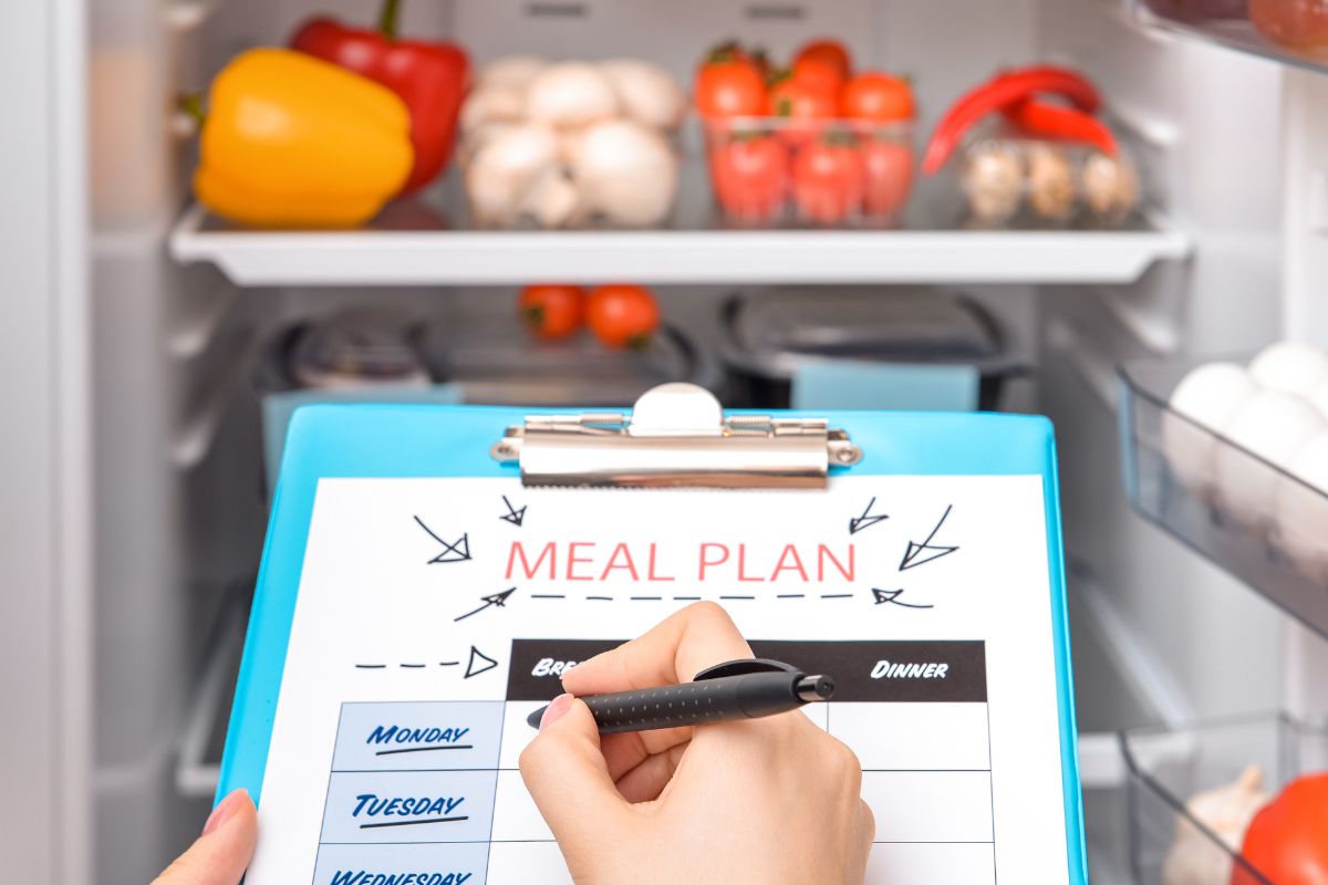 The photo shows a woman's hand making a meal plan.
