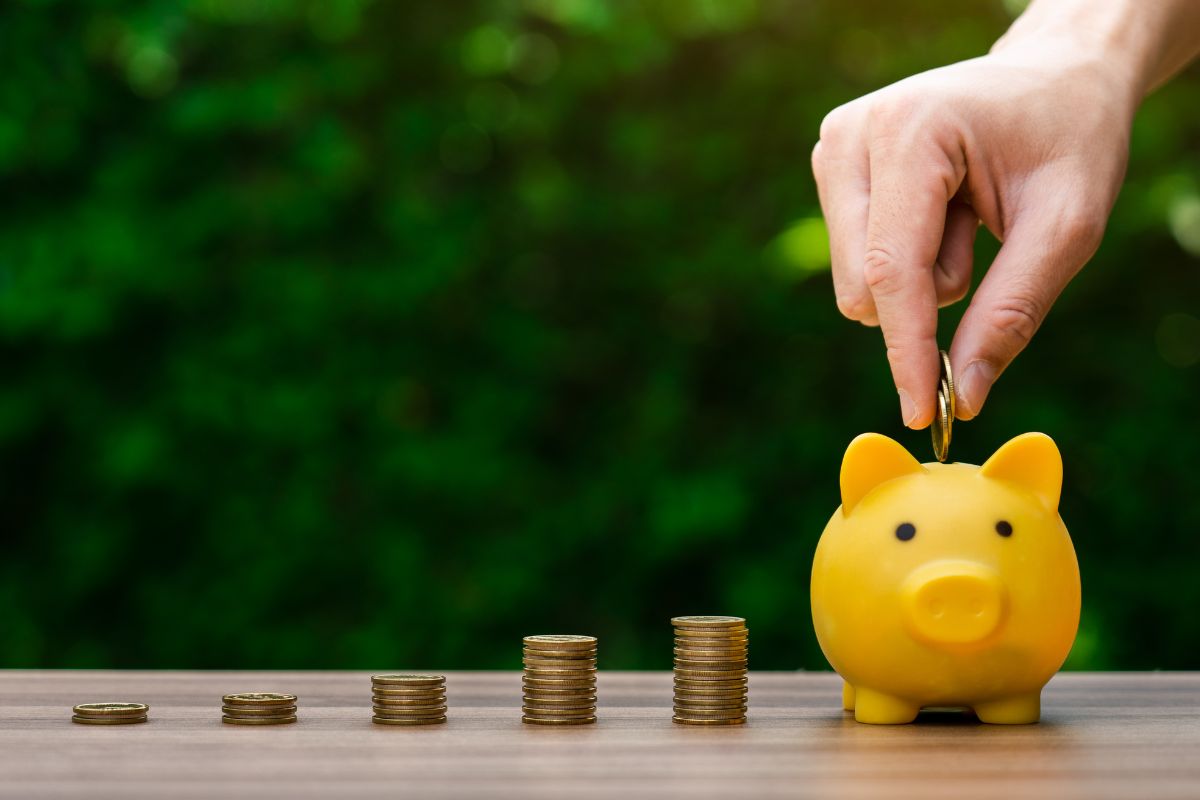 A man's hand saving money.