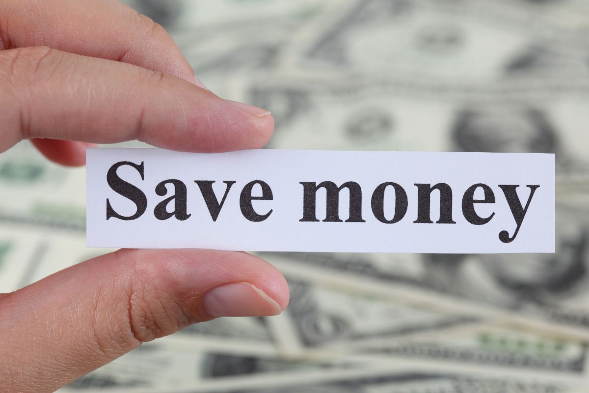 A woman's hand holding a paper with save money wording.