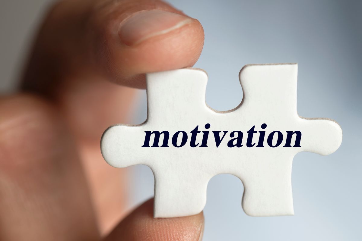 A man's hand holding a piece of a puzzle with motivation wording.