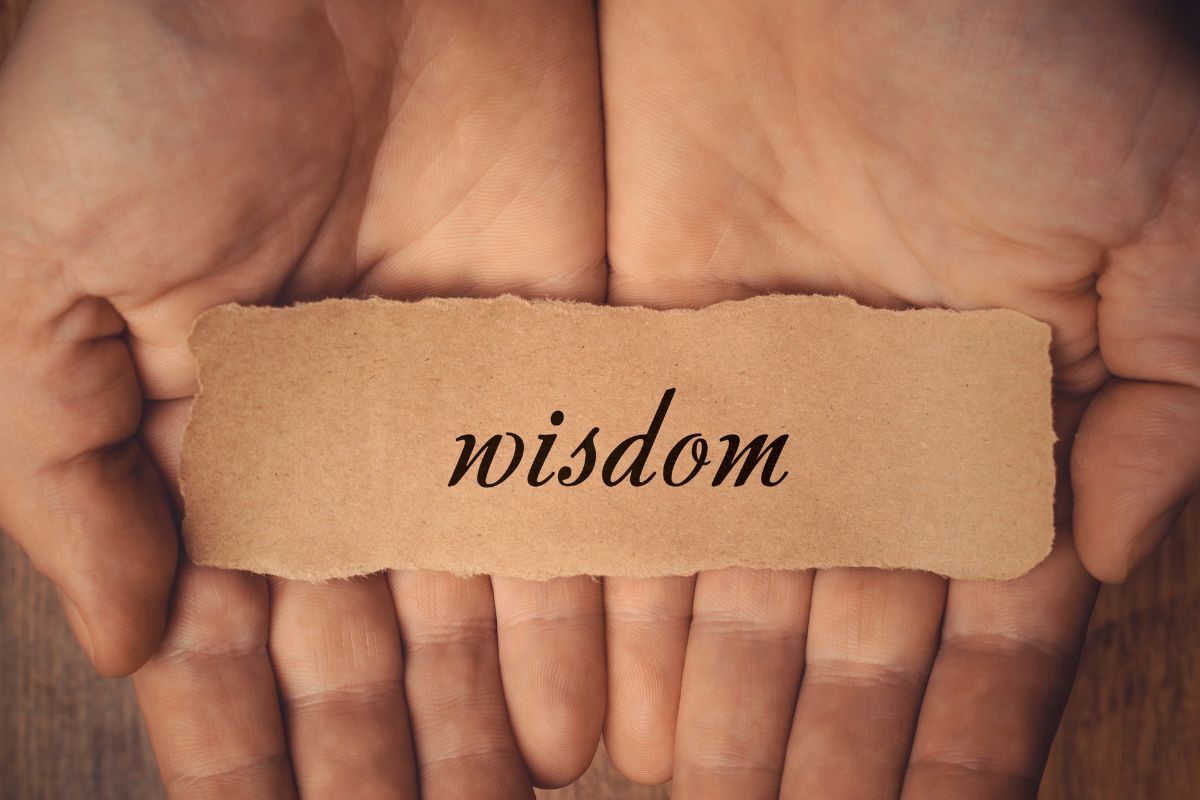 A man's hand holding a paper with wisdom wording.