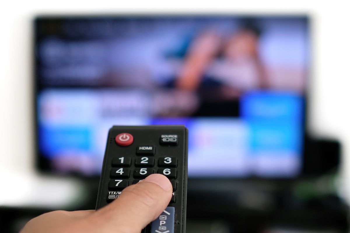 A man's hand watching a TV.