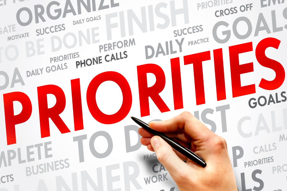 A woman's hand is writing priorities.