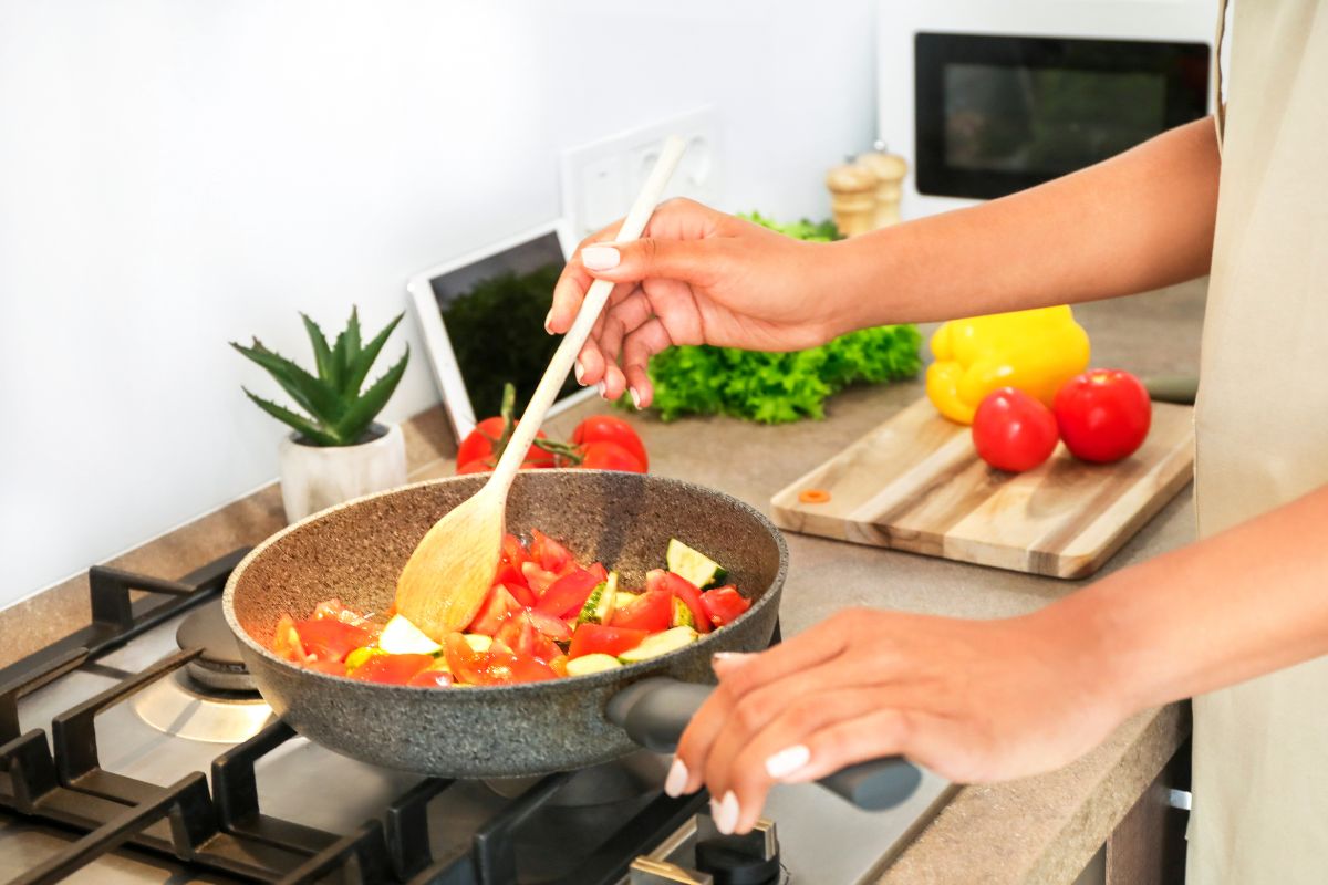 Picture of a woman's hand cooking meal at home.
