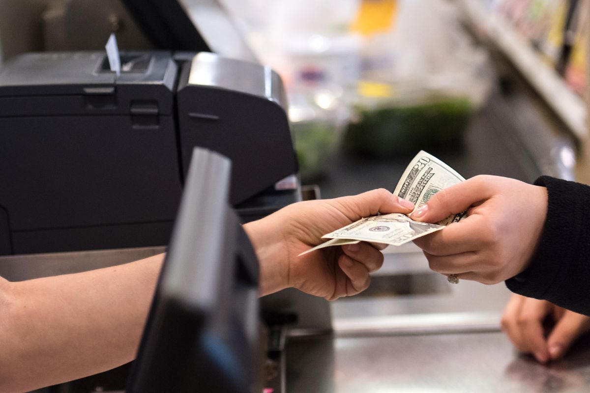 The picture shows a woman's hand paying with cash.
