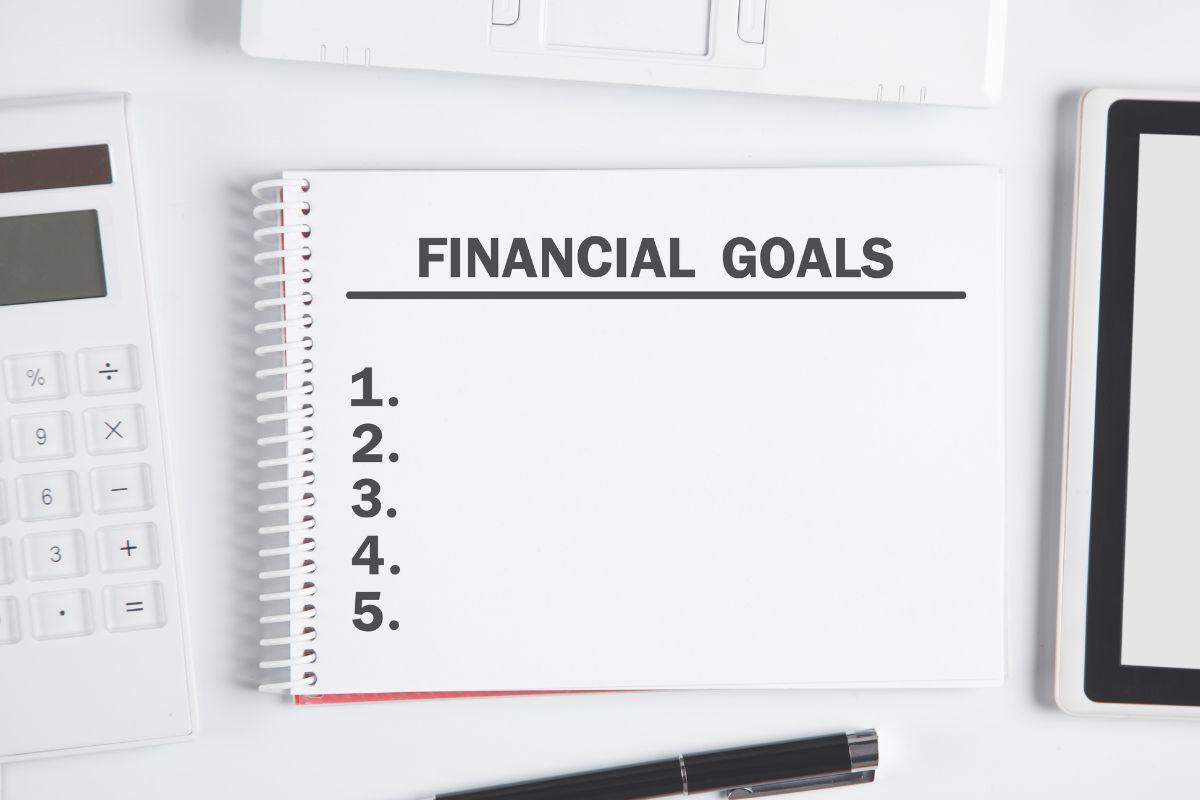 A imagem mostra um caderno com redação de metas financeiras.