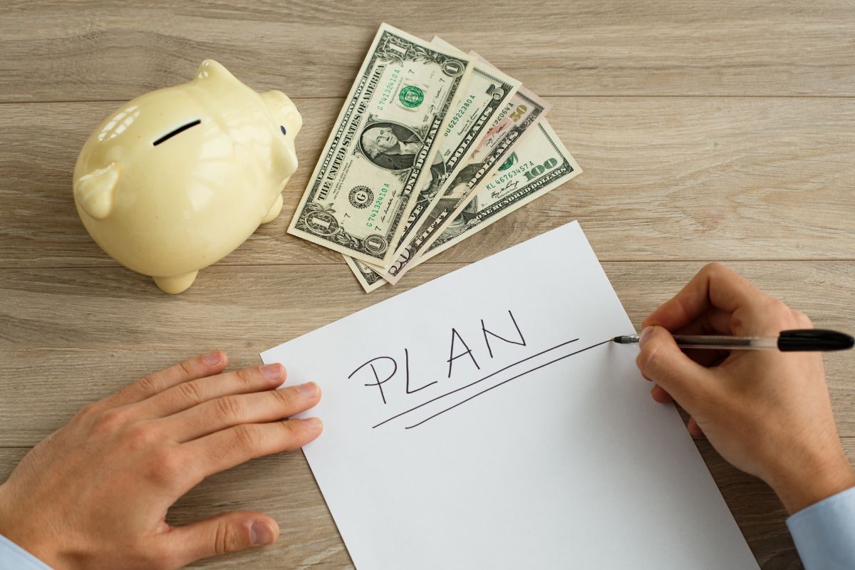 A man's hand is making a money plan.