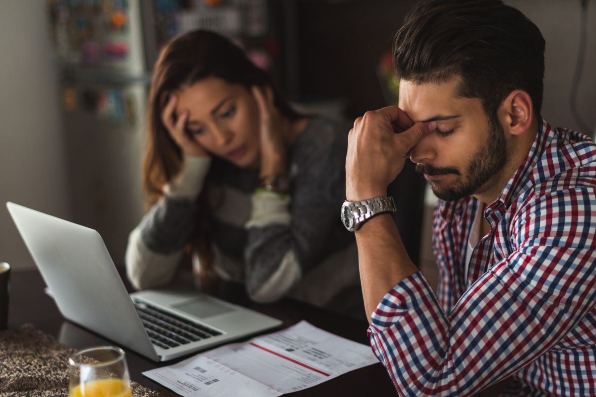 Picture shows a frustrated couple with debts.