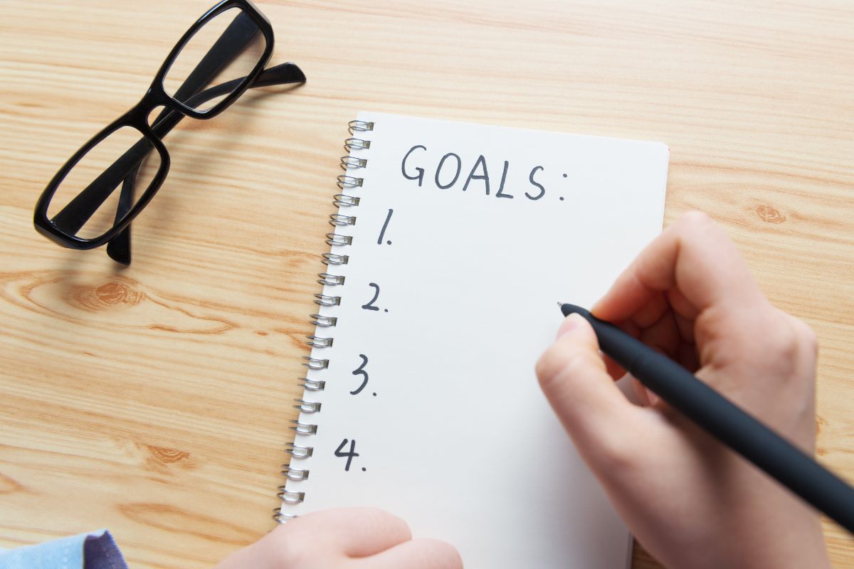 A young lady's hand is writing her goals.