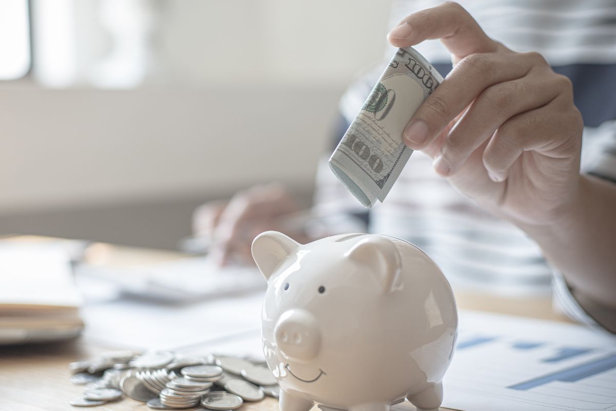 The image shows a woman's hand saving money.