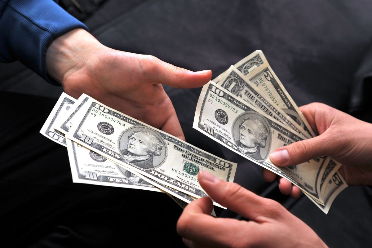 The picture shows a man's hand paying with cash.