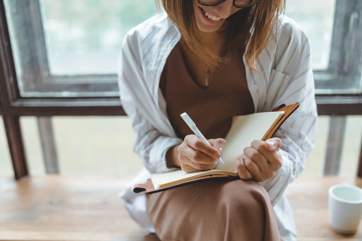 Picture of a woman writing her financial goals.