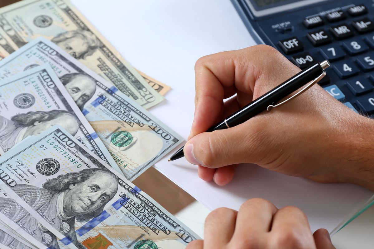 The picture shows a man's hand budgeting his money.