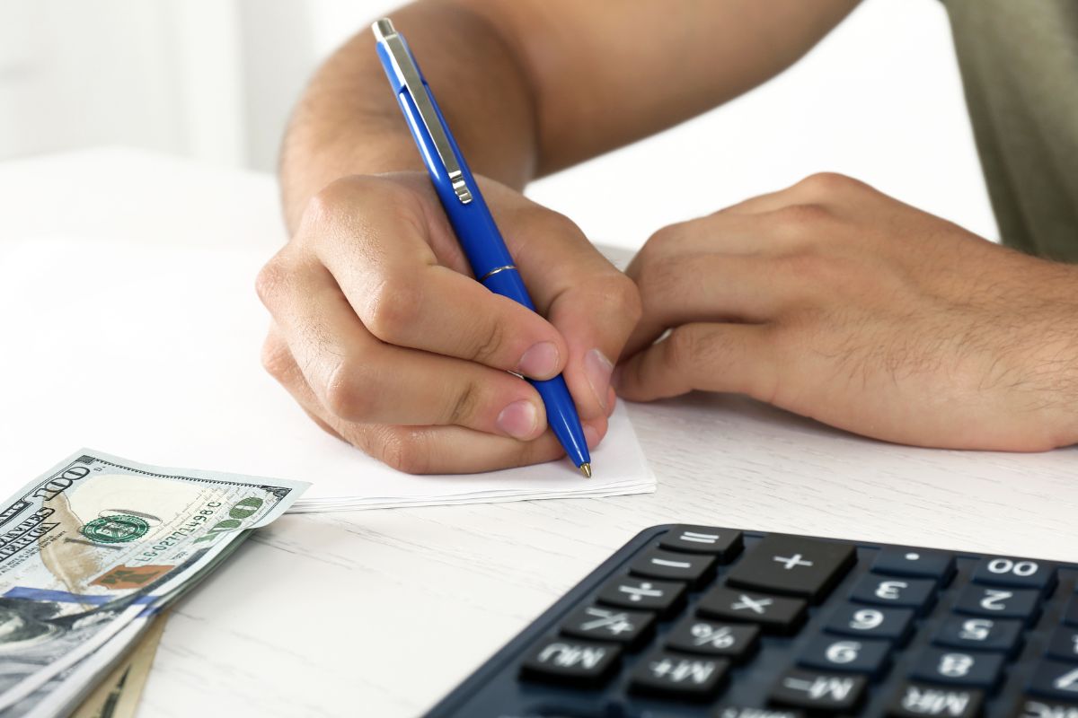 A man's hand reducing expenses.