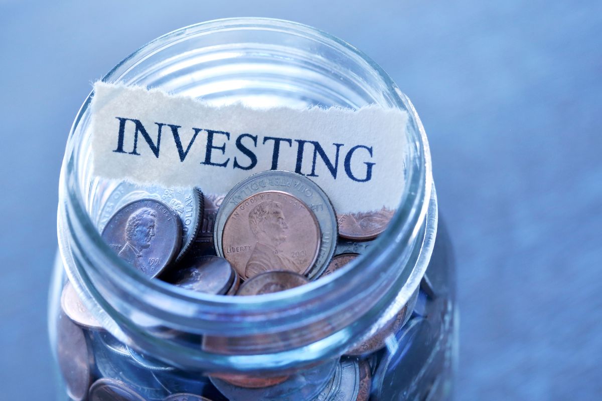 Photo of a jar with coins and investing wording.