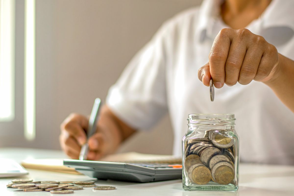 A man's hand savings money.