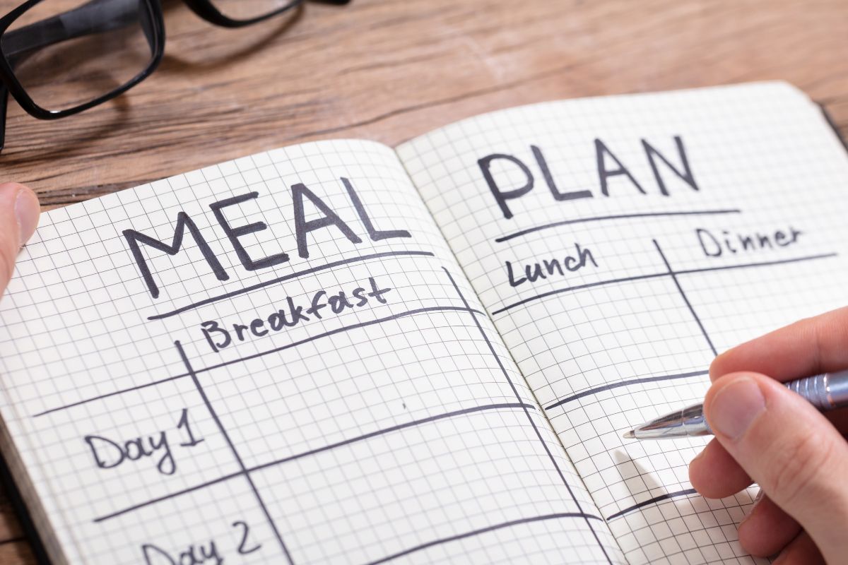 A man's hand making a meal plan.