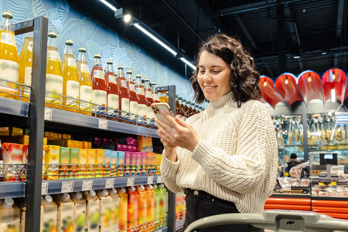 A woman using a phone while doing grocery shopping.
