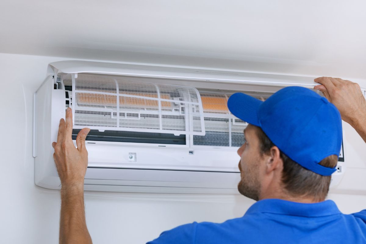 Image d'un homme réparant l'air conditionné.