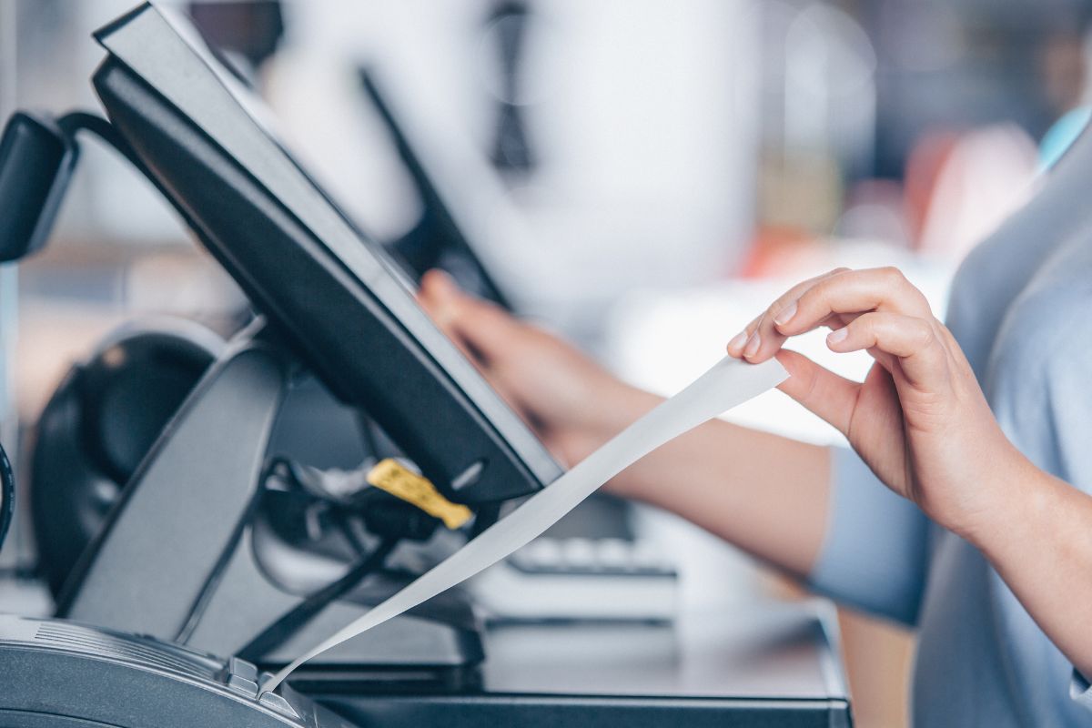 A cashier's hand and printing receipts.