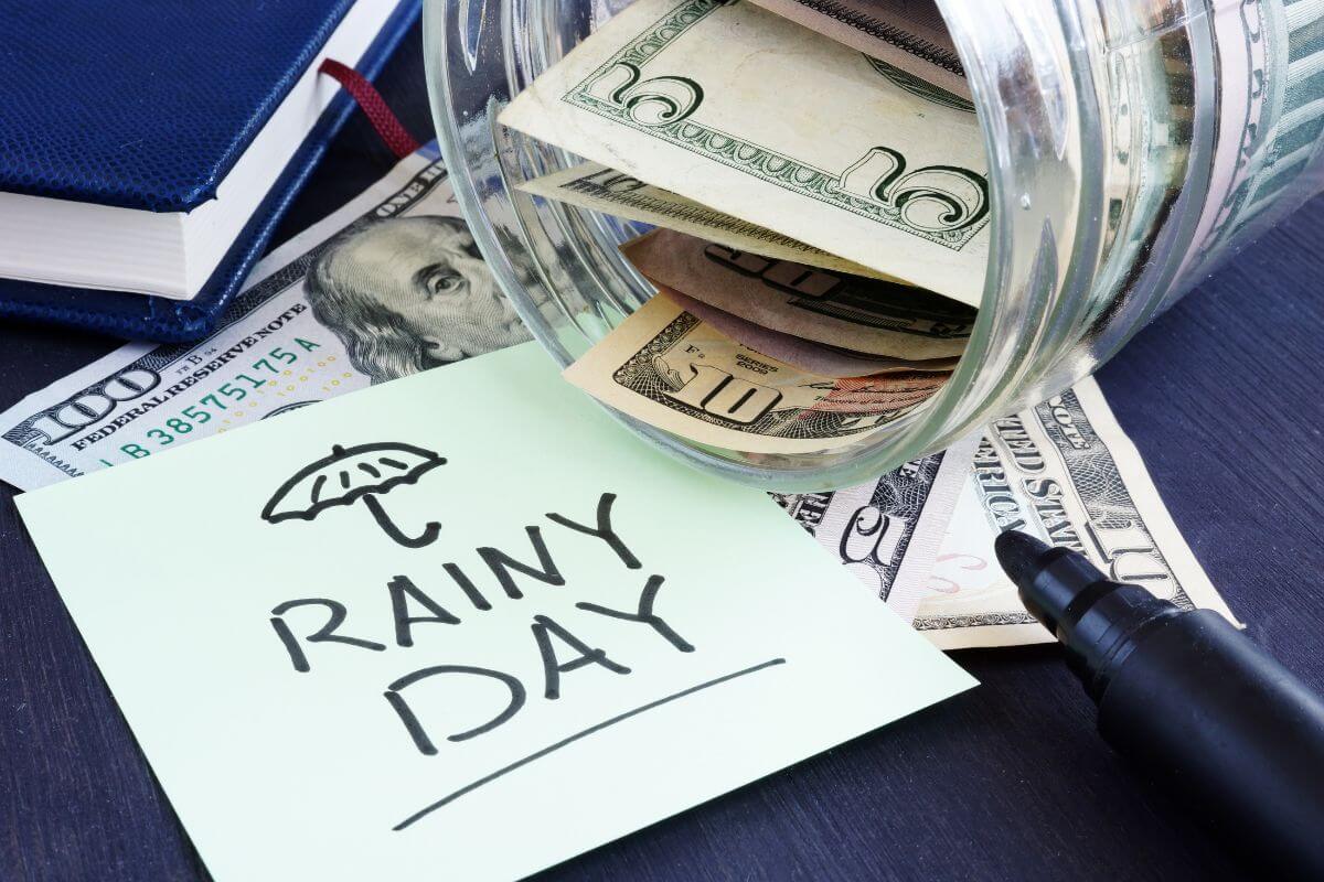 The image of the notebook, dollar bills, and note refers to a rainy day fund to cover minor unexpected expenses.