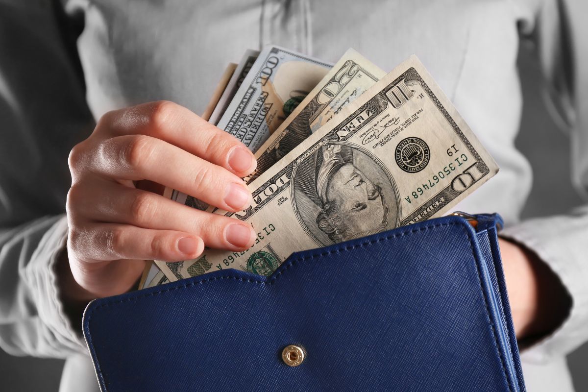 Image of a woman's hand putting money in her wallet.