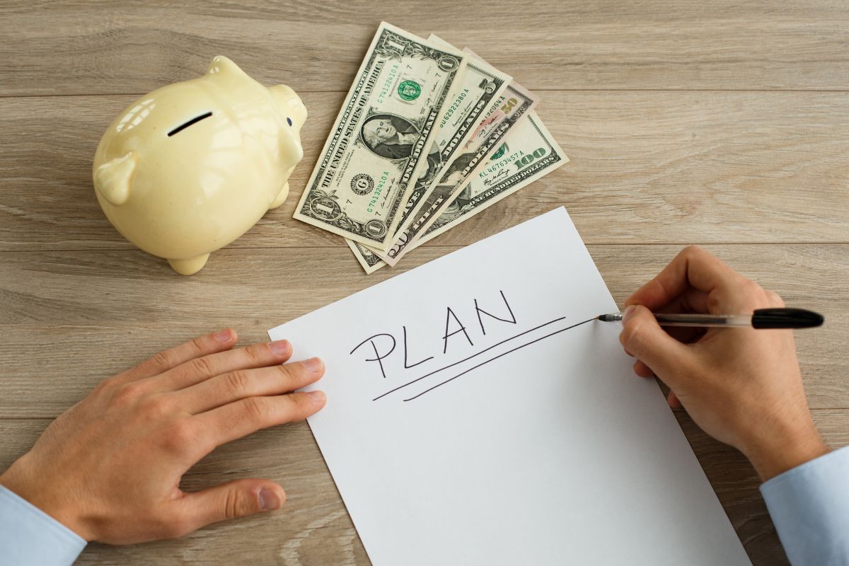 Image of a man's hand is writing plan in a paper with savings.