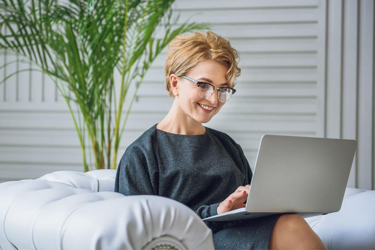 The picture tells about the girl sitting on a couch and using a laptop to start an Etsy shop and make money with your creative skills.