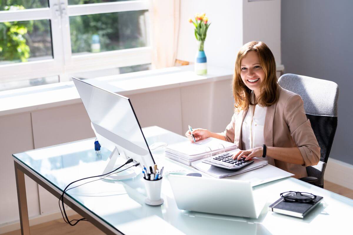 The picture of the girl starting a bookkeeping business in her office using a computer, calculator, and some papers for a steady source of income.