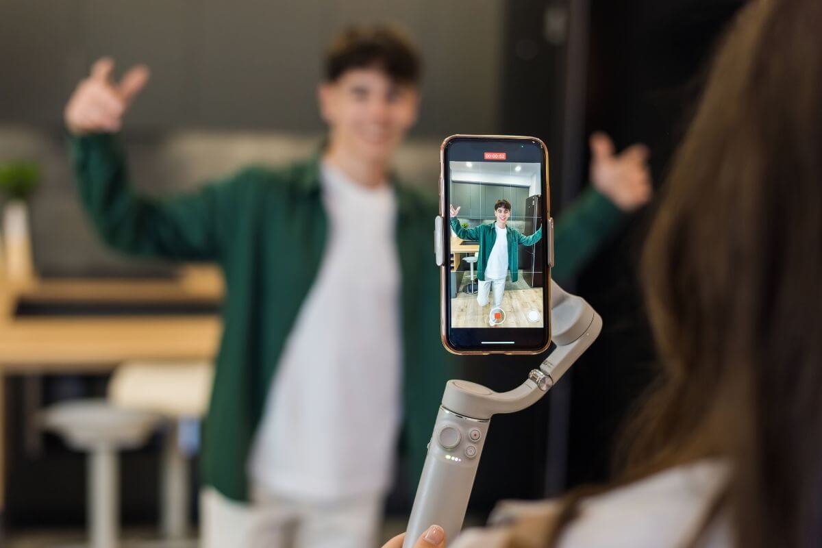 The image of the boy filming himself using a smartphone and becoming an influencer to build a following work with brands and earn money.