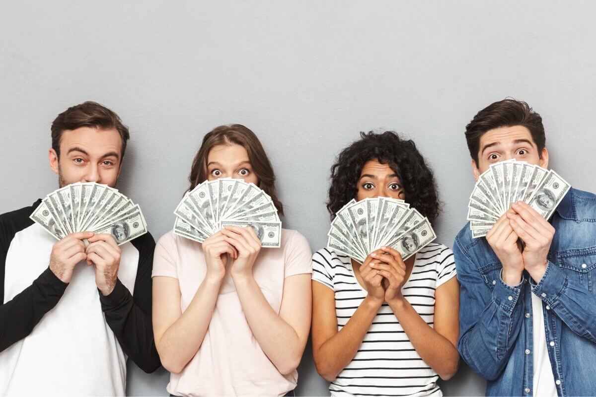 The picture shows a group of friends holding dollar bills and covering their faces indicating to take action to make $10k a month with these tips and guides.