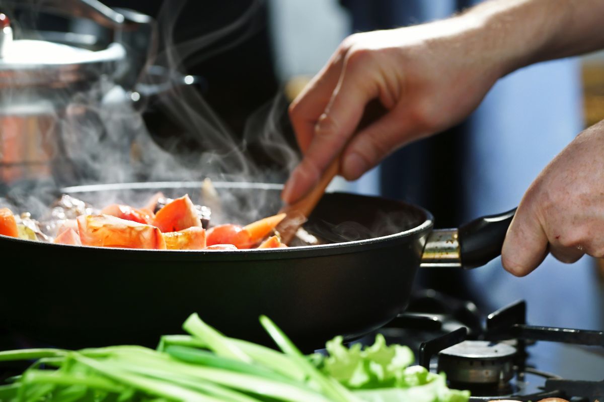 A man's hand and cooking meal at home.