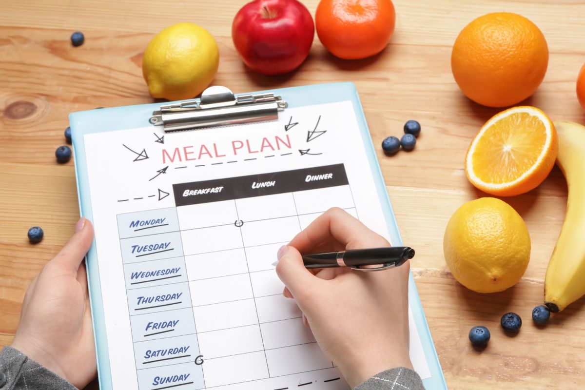 Photo of a woman's hand making a meal plan.