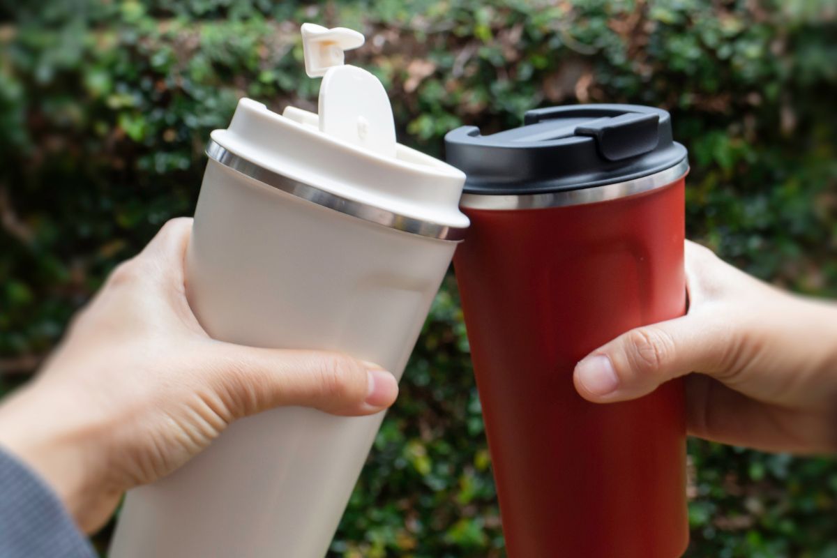 Picture of women's hands holding reusable thermos water.
